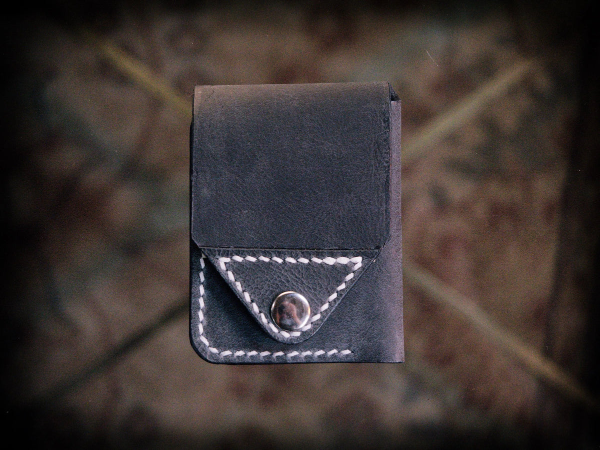 Handmade black chrome-tanned leather snap wallet, open showing three card pockets and cash pocket Black leather snap wallet with white saddle stitching, handmade in America Handmade snap wallet closed, black chrome-tanned leather with snap rivet closure
