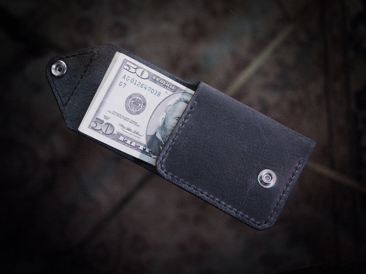Handmade black chrome-tanned leather snap wallet, open showing three card pockets and cash pocket Black leather snap wallet with white saddle stitching, handmade in America Handmade snap wallet closed, black chrome-tanned leather with snap rivet closure

