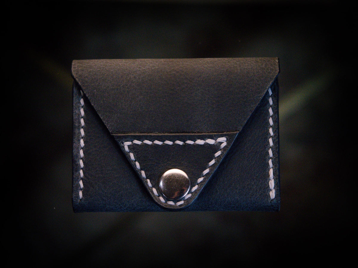 Handmade black chrome-tanned leather letter fold snap wallet, open showing two card pockets Black leather snap wallet with white saddle stitching, handmade in America Handmade letter fold snap wallet closed, black chrome-tanned leather with snap rivet closure
