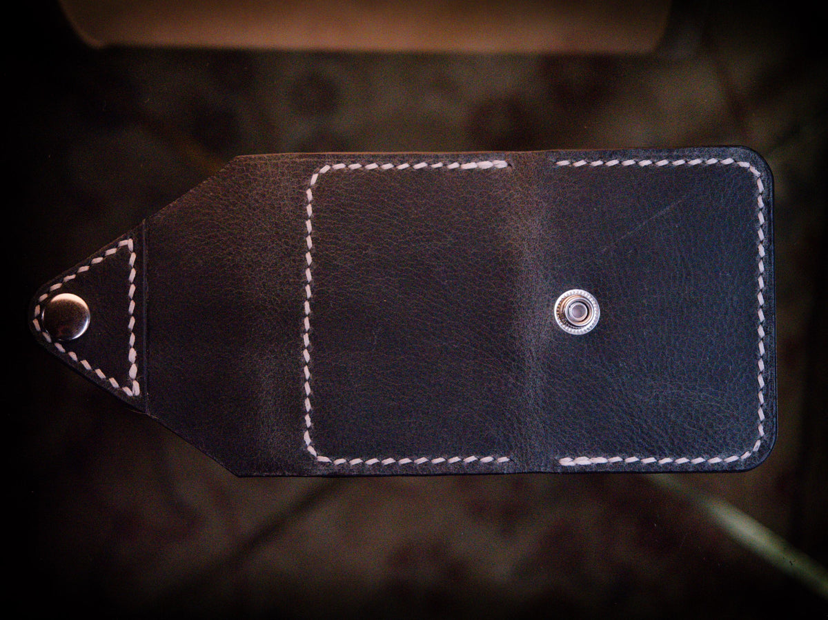 Handmade black chrome-tanned leather letter fold snap wallet, open showing two card pockets Black leather snap wallet with white saddle stitching, handmade in America Handmade letter fold snap wallet closed, black chrome-tanned leather with snap rivet closure
