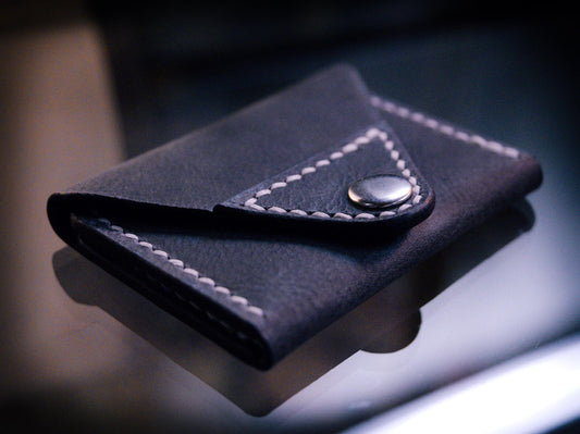 Handmade black chrome-tanned leather letter fold snap wallet, open showing two card pockets Black leather snap wallet with white saddle stitching, handmade in America Handmade letter fold snap wallet closed, black chrome-tanned leather with snap rivet closure
