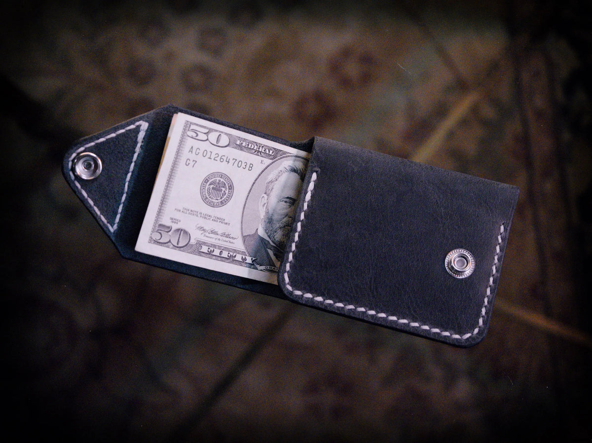 Handmade black chrome-tanned leather snap wallet, open showing three card pockets and cash pocket Black leather snap wallet with white saddle stitching, handmade in America Handmade snap wallet closed, black chrome-tanned leather with snap rivet closure
