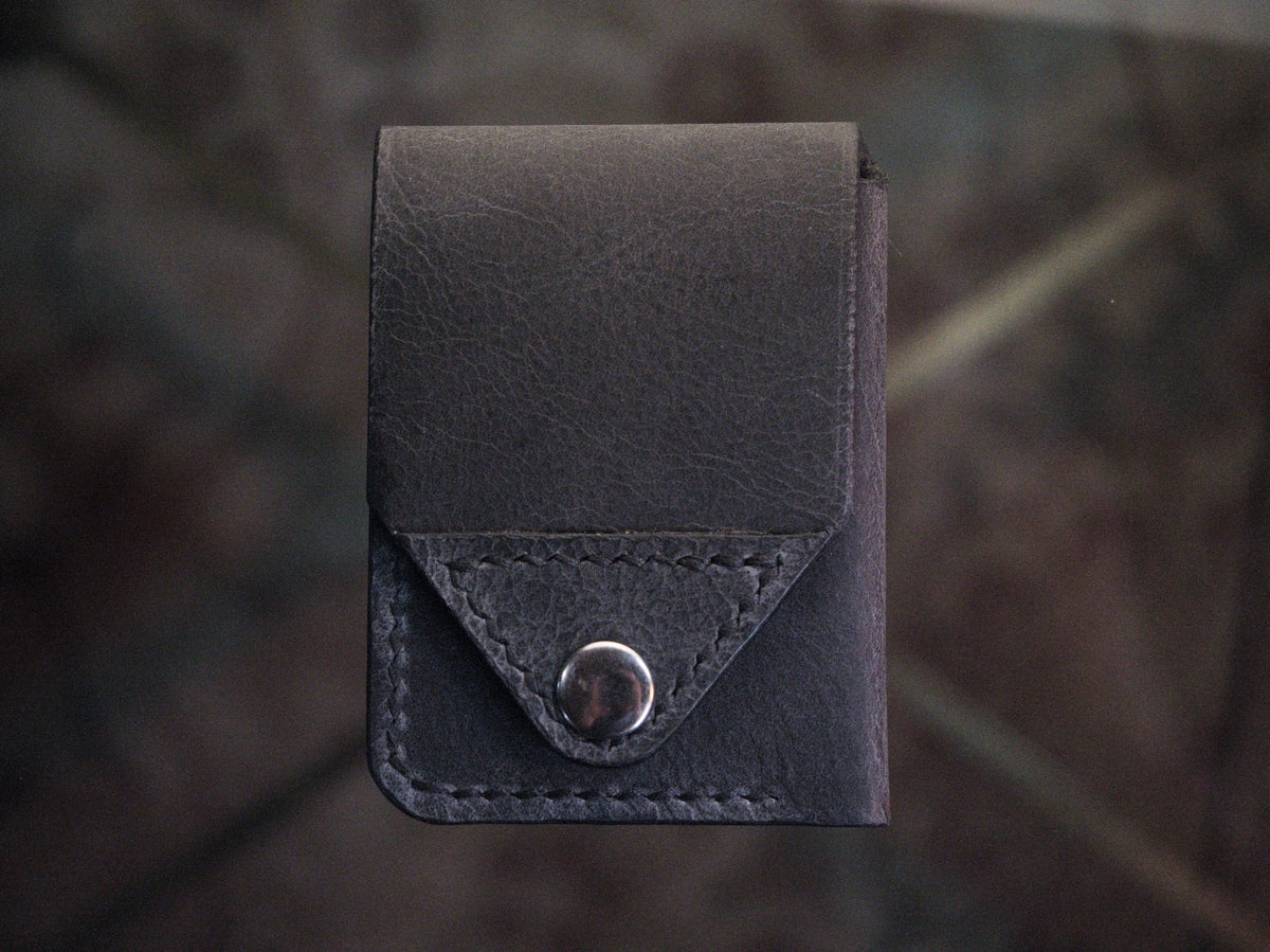 Handmade black chrome-tanned leather snap wallet, open showing three card pockets and cash pocket Black leather snap wallet with white saddle stitching, handmade in America Handmade snap wallet closed, black chrome-tanned leather with snap rivet closure
