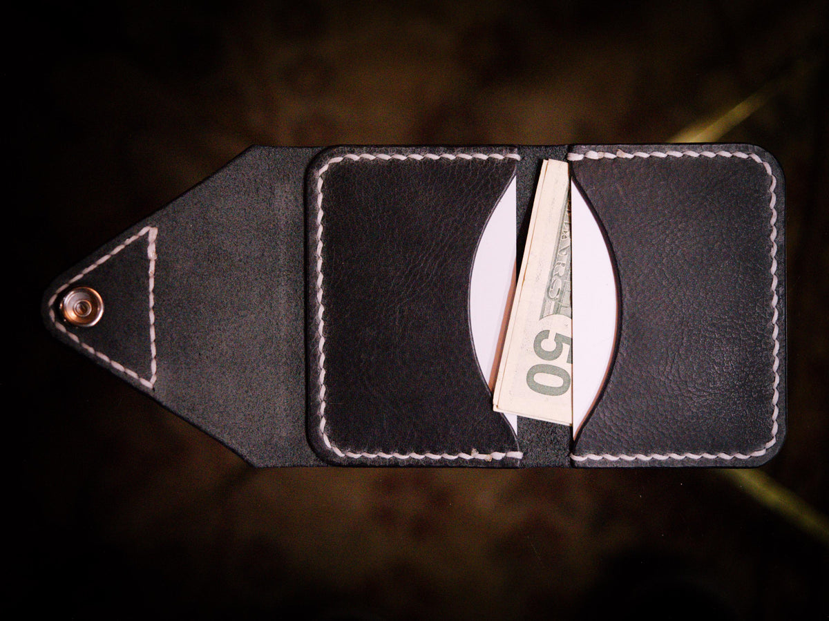 Handmade black chrome-tanned leather letter fold snap wallet, open showing two card pockets Black leather snap wallet with white saddle stitching, handmade in America Handmade letter fold snap wallet closed, black chrome-tanned leather with snap rivet closure
